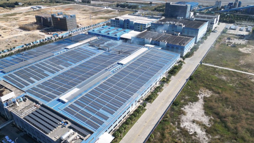 Vista aérea de painéis solares instalados sobre um complexo industrial.