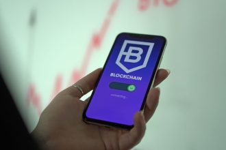 Mão segurando um smartphone com a tela de uma carteira digital de criptomoedas e tecnologia blockchain.