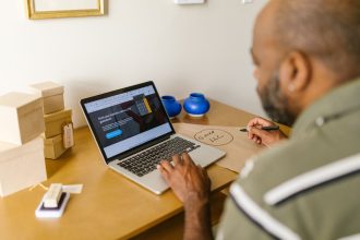 Empreendedor trabalha em uma mesa usando um laptop em um ambiente de escritório.