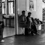 Três pessoas reunidas em um centro comunitário, em ambiente interno.