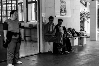 Três pessoas reunidas em um centro comunitário, em ambiente interno.