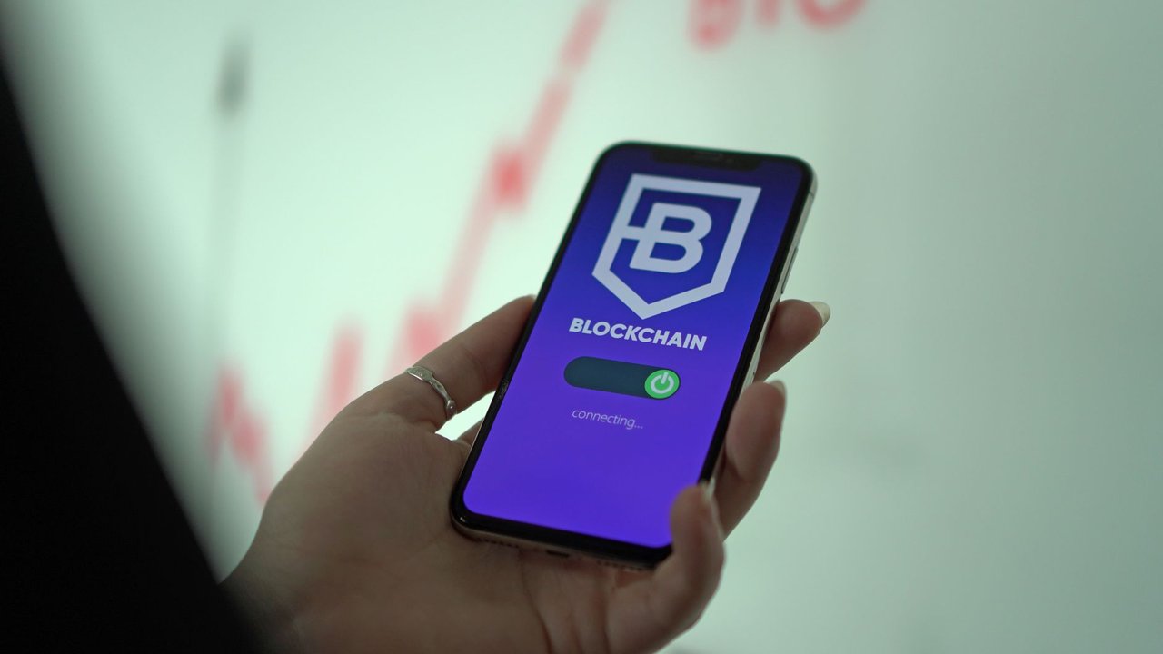 Mão segurando um smartphone com a tela de uma carteira digital de criptomoedas e tecnologia blockchain.