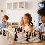 Estudantes disputam uma partida de xadrez em uma sala de aula.