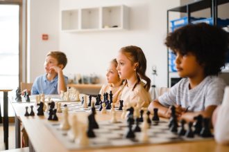Estudantes disputam uma partida de xadrez em uma sala de aula.