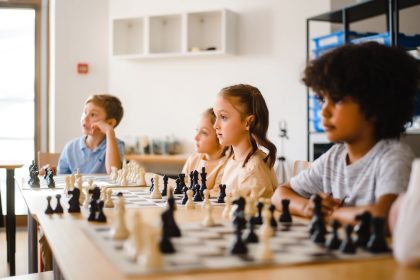 Estudantes disputam uma partida de xadrez em uma sala de aula.